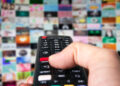 black remote control in hand over smart tv background, channel switching