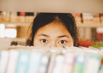 In the library - Young girl student with books working in a high school library.