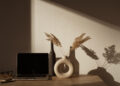 Laptop computer with blank screen on table with pampas grass bouquet in sunlight shadows on the wall. Aesthetic influencer boho styled office workspace interior design template with mockup copy space