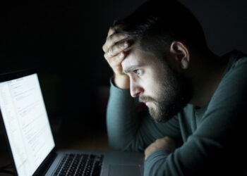 Man in front of the laptop reading and being concentrated.