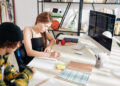 Teenagers learning computer science at home, doing homework and taking notes in textbooks